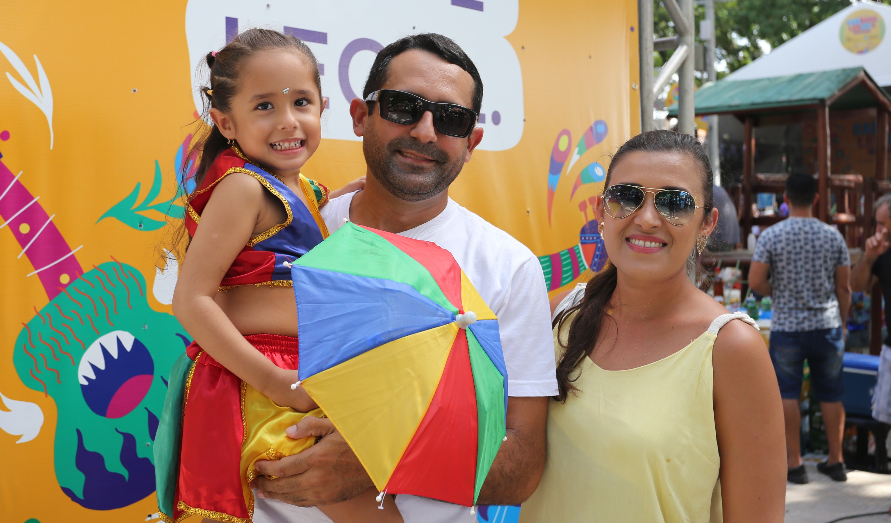 pai com filha no colo e mãe ao lado todos sorrindo para a foto